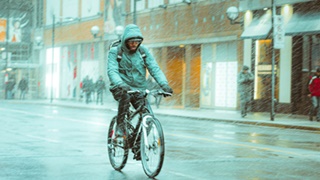 雨の中を合羽を着てロードバイクに乗る人